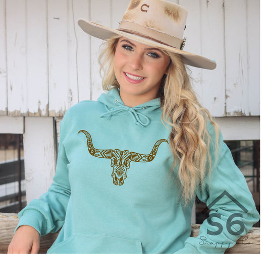 Screen print transfer for sale for use on graphic tees western steer head. Young woman leaning against fence with blue sweatshirt with screenprint trasnfer design pressed onto shirt 