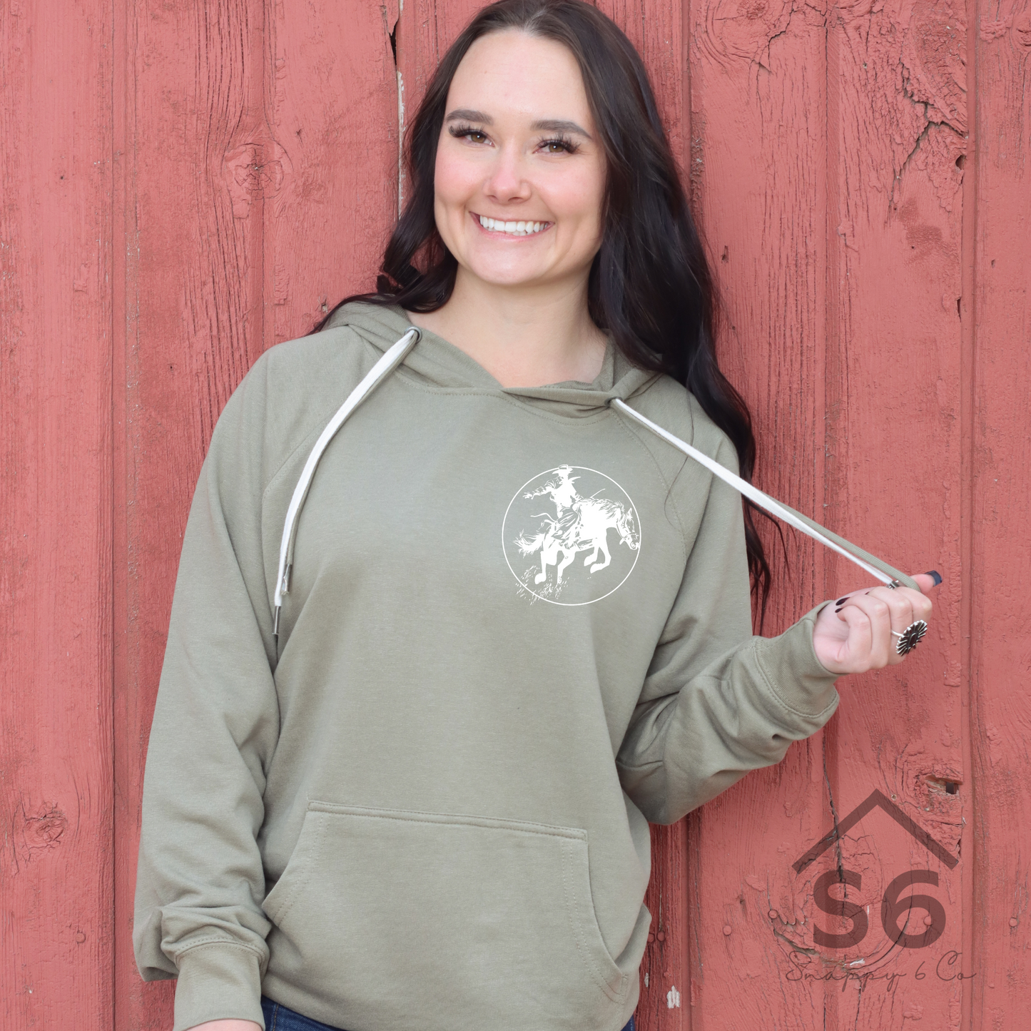 woman wearing a sweatshirt with a pocket sized bucking horse on it. 